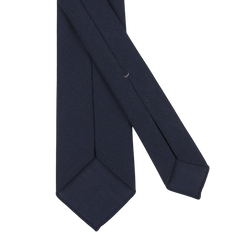 A close-up of a Dreaming Of Monday Navy Blue Wool Fresco 7-Fold Tie with a slim width and pointed ends, crafted from pure high-twist wool, set against a plain white background.