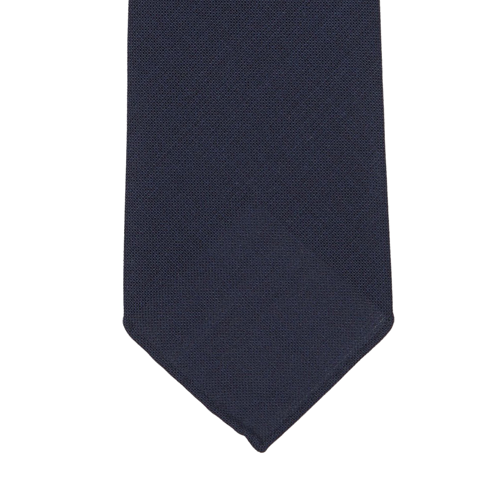 Navy blue tie with a subtle textured pattern, shown flat against a white background, showcasing its exquisite 7-fold construction, handmade in Sweden. Introducing the Navy Blue Wool Fresco 7-Fold Tie by Dreaming Of Monday.