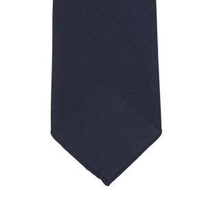 Navy blue tie with a subtle textured pattern, shown flat against a white background, showcasing its exquisite 7-fold construction, handmade in Sweden. Introducing the Navy Blue Wool Fresco 7-Fold Tie by Dreaming Of Monday.
