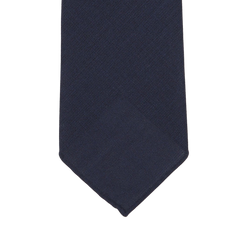 Navy blue tie with a subtle textured pattern, shown flat against a white background, showcasing its exquisite 7-fold construction, handmade in Sweden. Introducing the Navy Blue Wool Fresco 7-Fold Tie by Dreaming Of Monday.