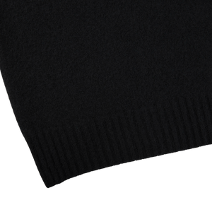 A close up of a Drumohr Black Brushed Lambswool High Neck Sweater on a white surface.