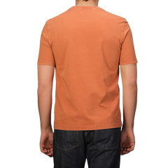 A person wearing Drumohr's Burnt Orange Washed Cotton T-Shirt paired with dark jeans, highlighting its slim fit, stands against a plain background.