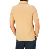 Rear view of a person wearing a Cappuccino Beige Cotton Piquet Drumohr slim fit polo shirt and dark trousers.