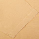 Close-up of Cappuccino Beige Drumohr slim fit polo shirt fabric with a sewn seam and folded edge.