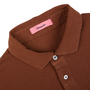 Close-up of a coffee brown Drumohr polo shirt collar with a pink brand label.
