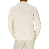 The man is seen from behind, dressed in a Drumohr ecru white knitted cotton cardigan.