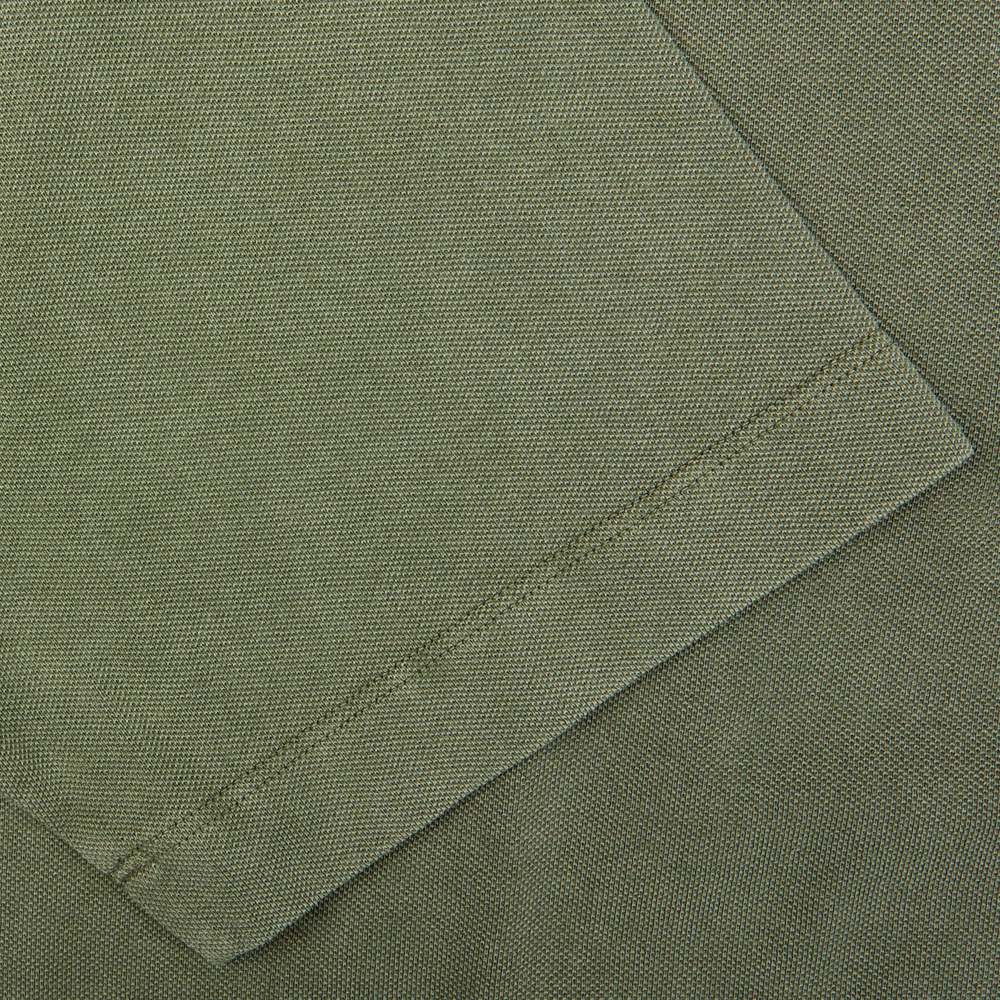 Close-up of a grass green Drumohr cotton piquet polo shirt with a sewn pocket detail.