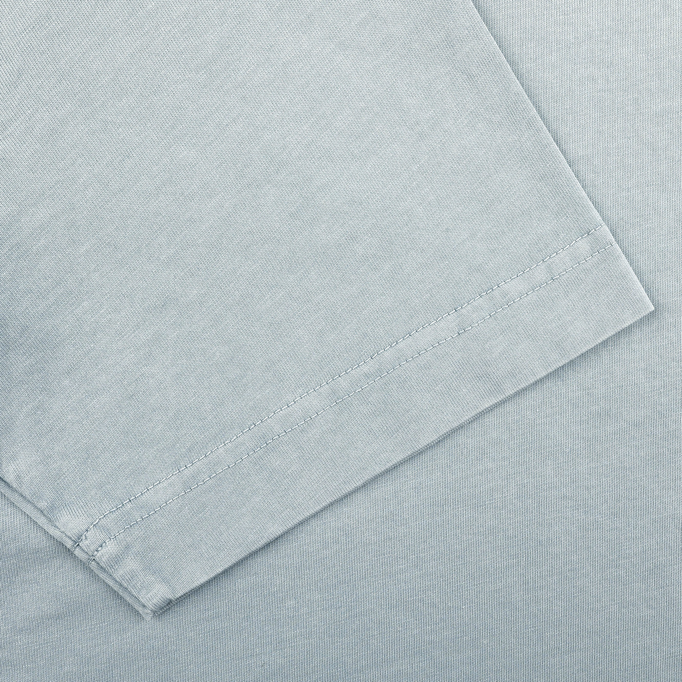 Close-up of the corner of a Sky Blue Washed Cotton T-Shirt by Drumohr, highlighting stitching details and texture.