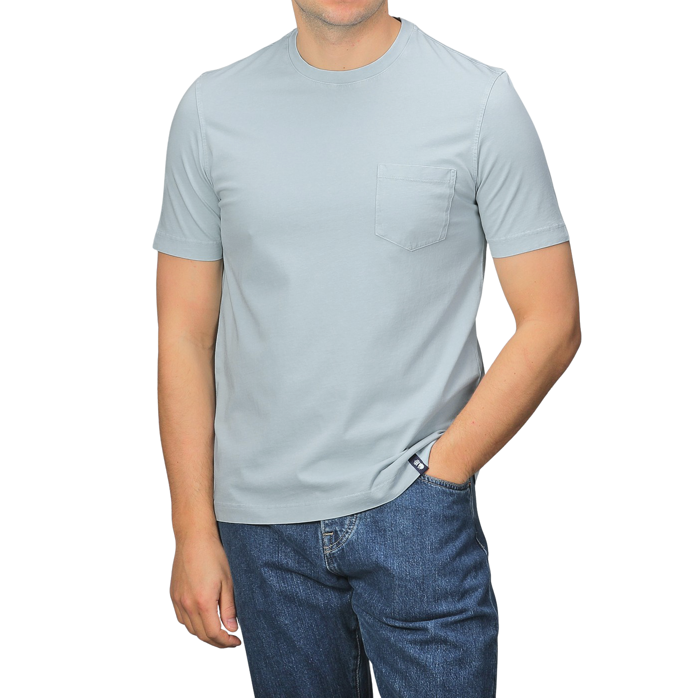 A person in a slim-fit, light gray Drumohr T-shirt with a chest pocket and sky blue jeans stands with one hand in their pocket.