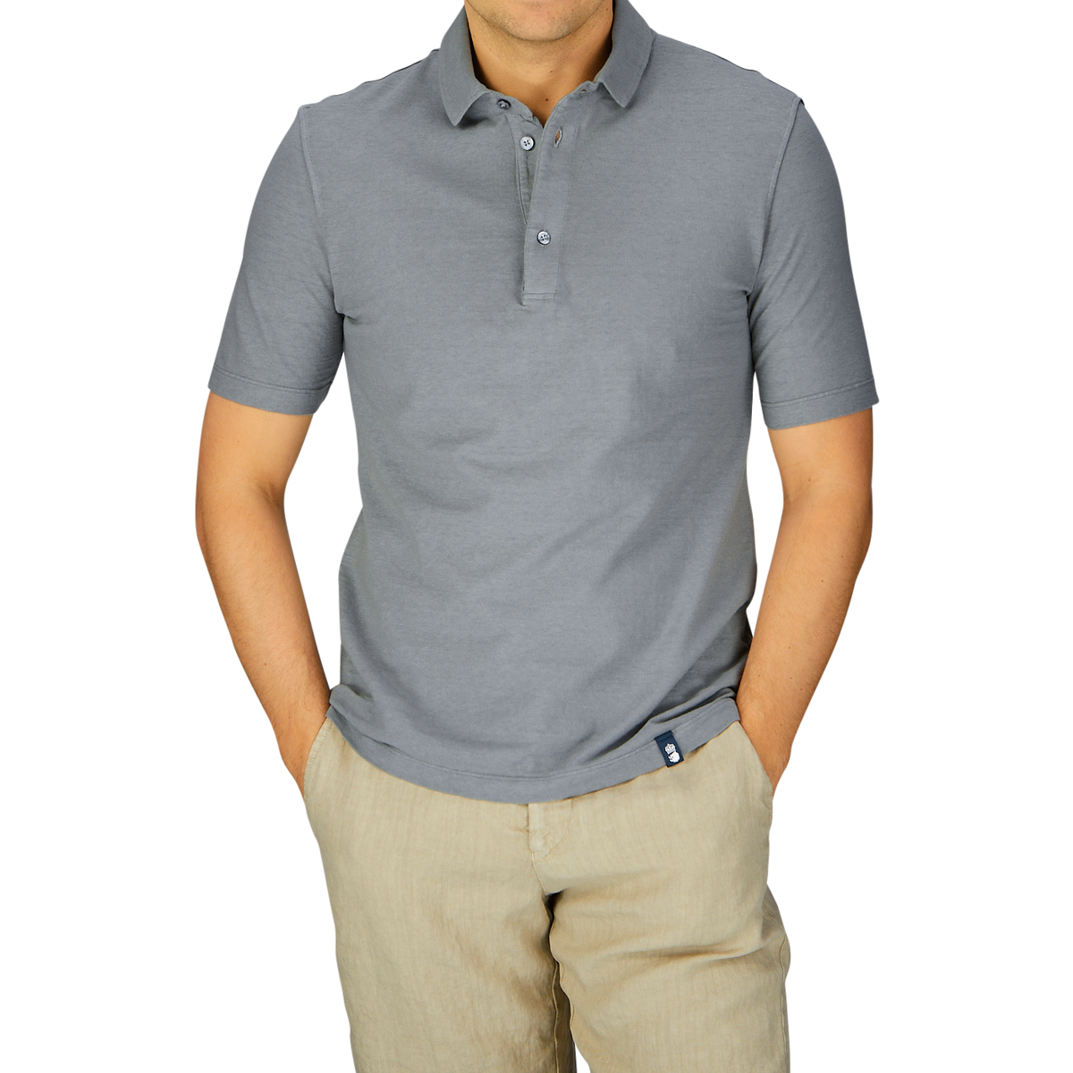 Man wearing a Drumohr steel grey cotton linen polo shirt and beige pants against a gray background.