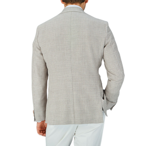 The back view of a man wearing a Grey Beige Houndstooth Wool Blend Sendrik Blazer and white pants, with an Eduard Dressler touch to it.