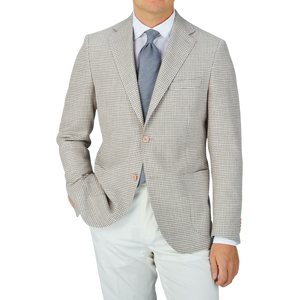 A man wearing an Eduard Dressler Grey Beige Houndstooth Wool Blend Sendrik Blazer and white pants.