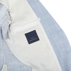 A Eduard Dressler Light Blue Herringbone Cotton Linen Sendrik Blazer with a label on it.