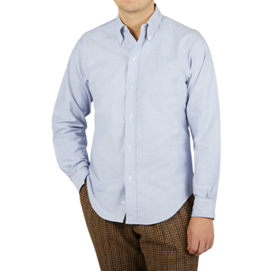 A man wearing a Far East Manufacturing light blue cotton oxford BD regular shirt and brown pants made of cotton fabric.