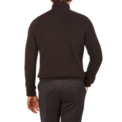 A person wearing the Fedeli Dark Brown Wool Cashmere Rollneck and gray pants stands with their left hand in their pocket.