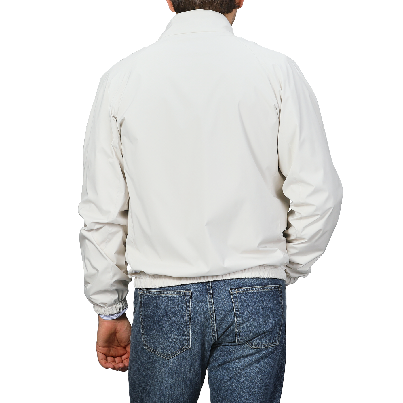 A person wearing a Fedeli Beige Nougat Nylon Reversible Blouson Jacket and blue jeans stands against a gray background, facing away from the camera.