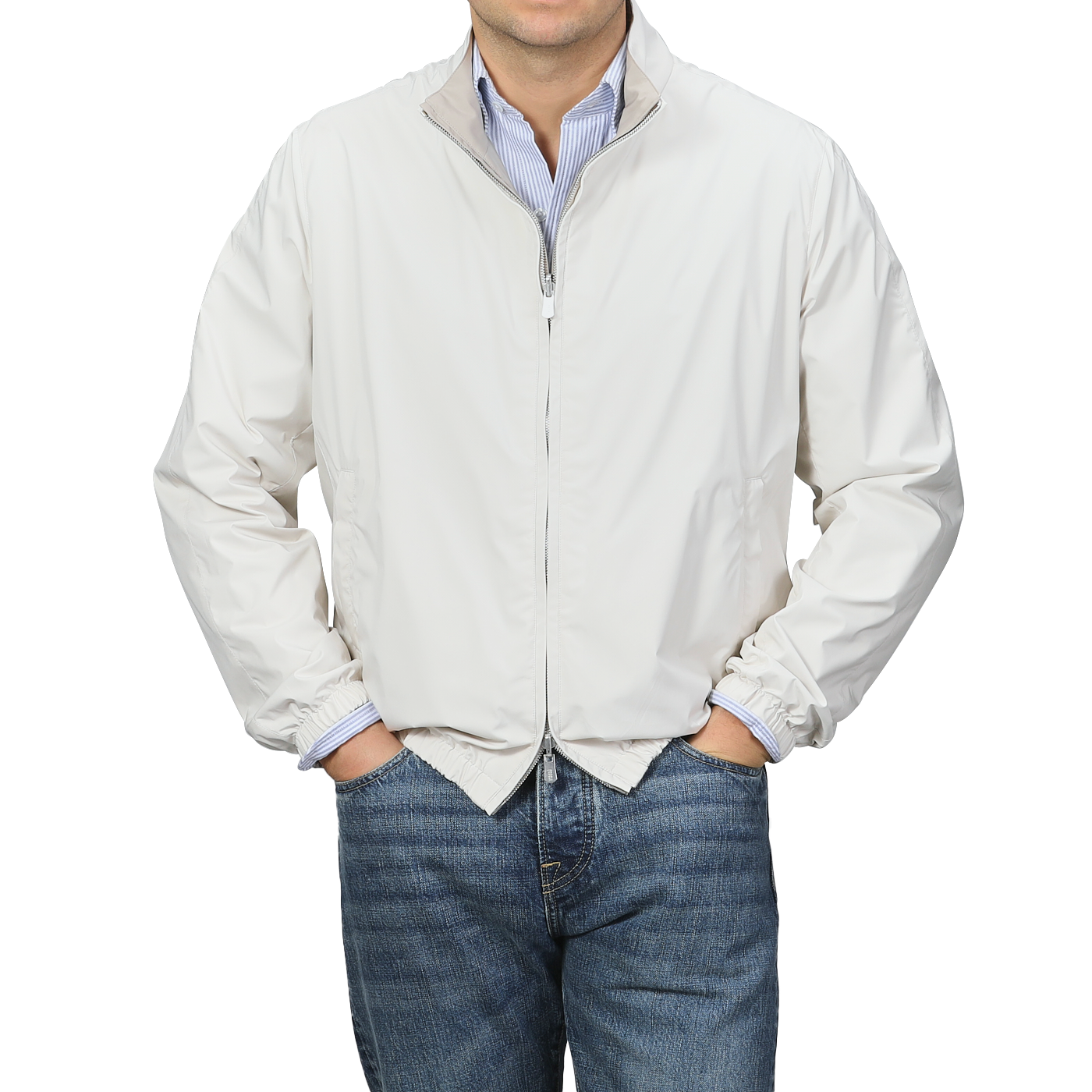 Man in a beige nougat nylon reversible Fedeli blouson jacket over a blue striped shirt with jeans, against a gray background.