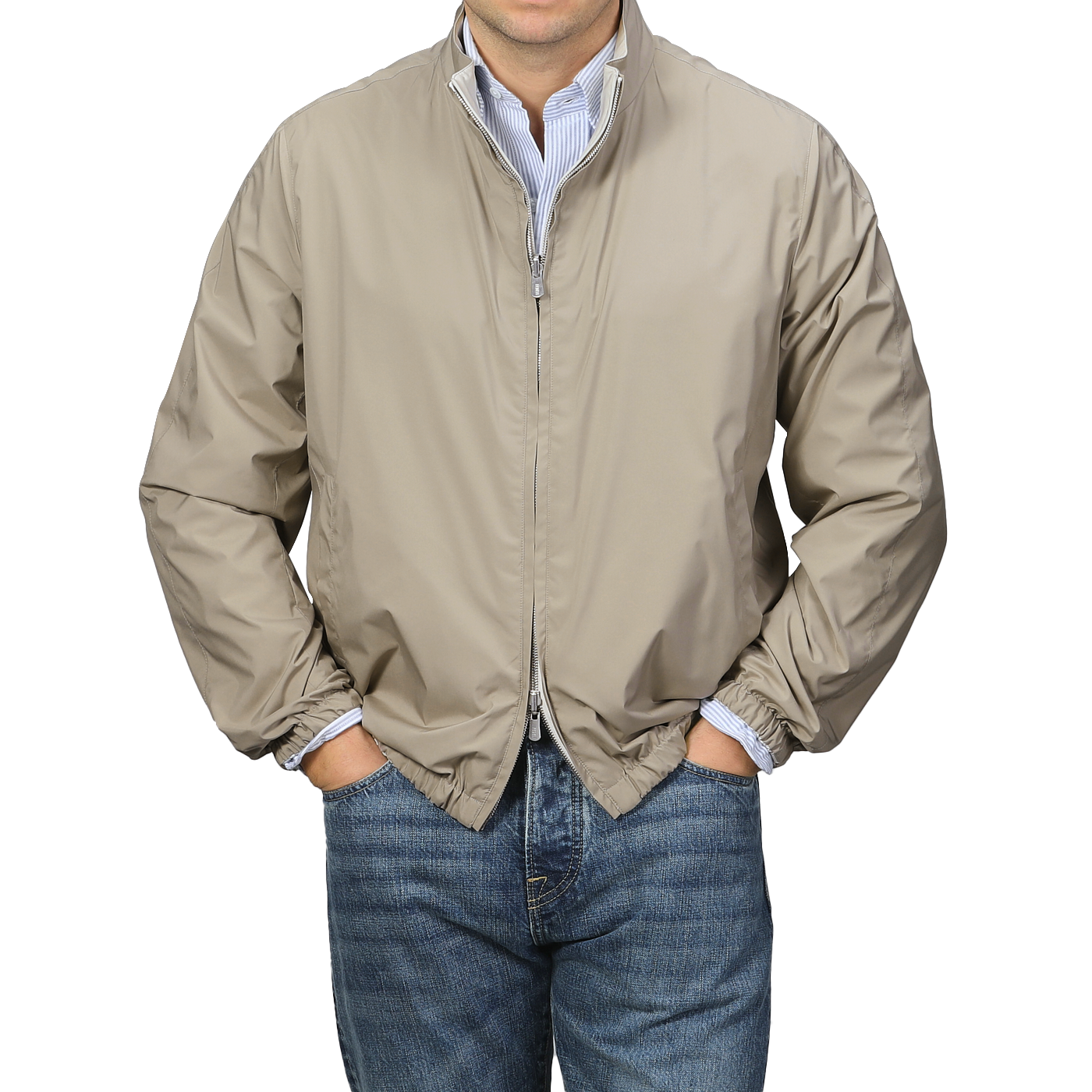 A person wearing a Fedeli Beige Nougat Nylon Reversible Blouson Jacket with a two-way zip closure, paired with blue jeans, stands with hands in pockets against a neutral background.