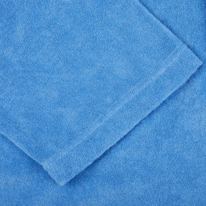 A bright blue cotton towel on a white surface by Fedeli.