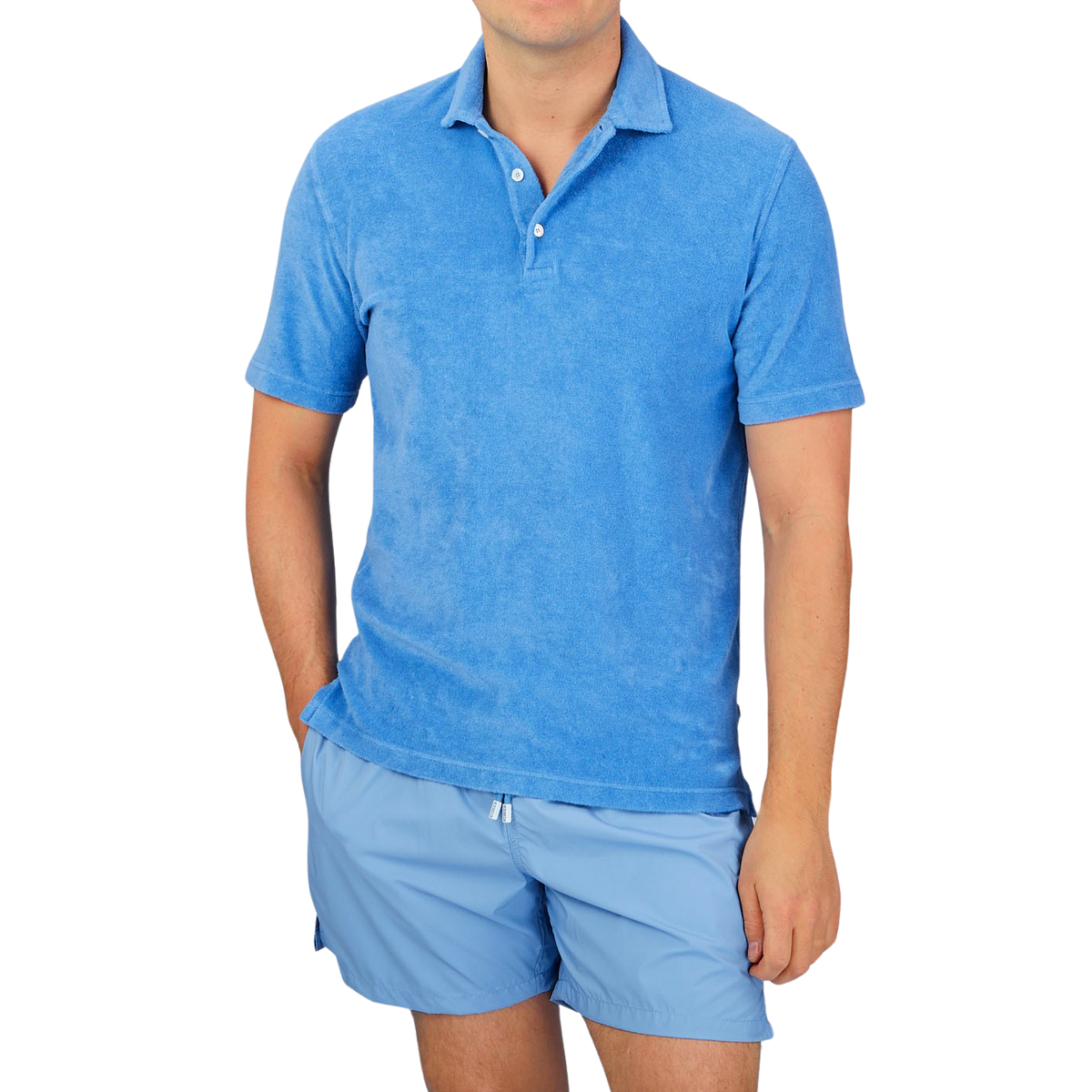 A man wearing a Fedeli Bright Blue Cotton Towelling Polo Shirt and shorts, his summer favorite.