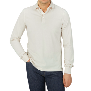 A luxury casual wear producer, Fedeli, creating high-quality Cream Beige Organic Cotton LS Polo Shirts. The man is wearing a white polo shirt and jeans.