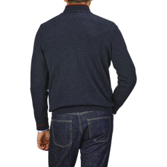 A person wearing the Fedeli Dark Blue Wool Cashmere 1/4 Zip Sweater and blue jeans is viewed from the back against a plain gray background. Their left hand is resting on their hip, showcasing the cozy wool-cashmere blend of their top.