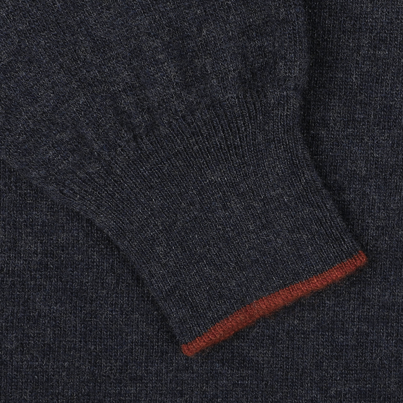 Close-up of a dark blue Fedeli wool-cashmere blend 1/4 zip sweater sleeve with a red border on the cuff.