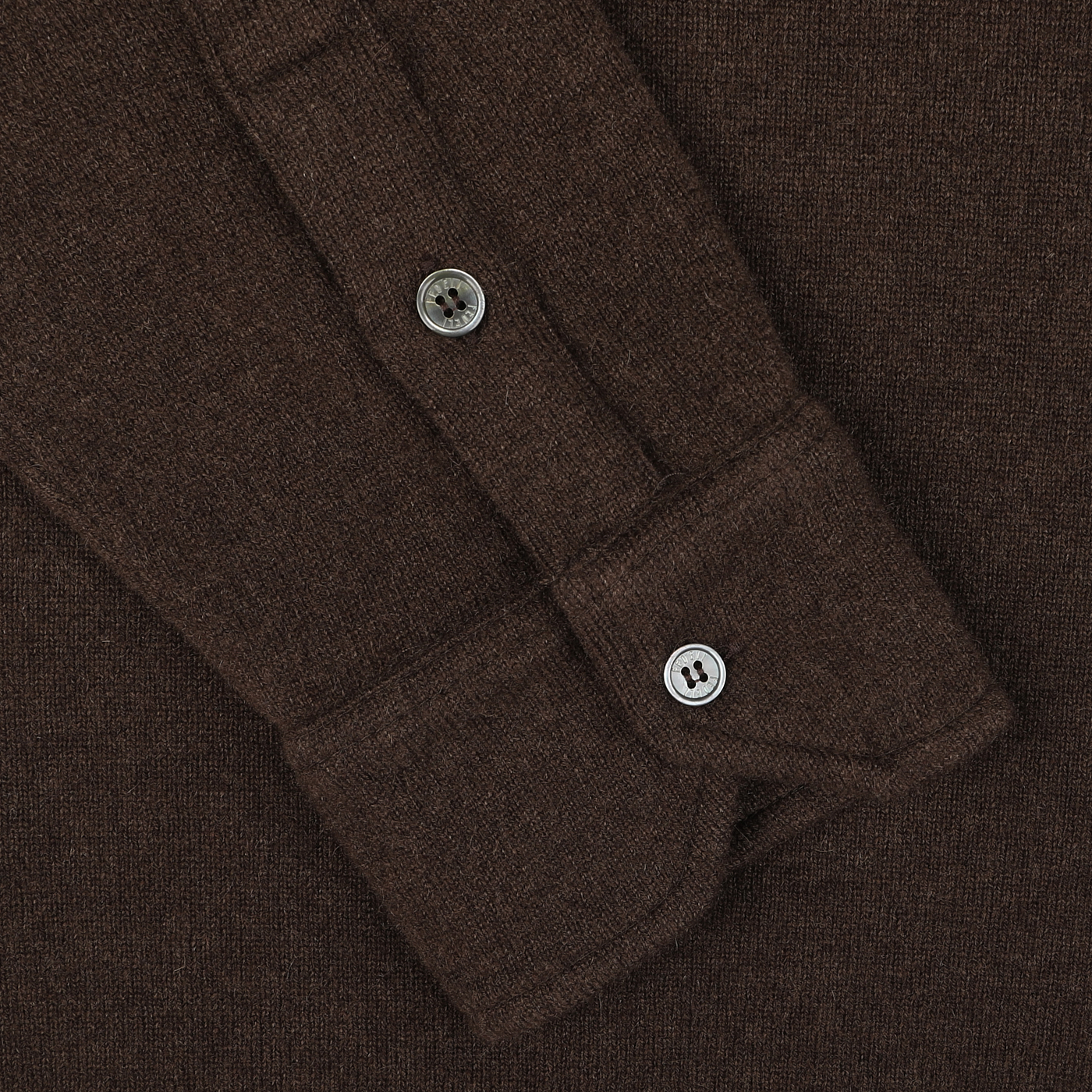 Close-up of the cuff of the luxurious Dark Brown Felted Cashmere Overshirt by Fedeli, highlighting its elegant brown long-sleeved design with one button fastened and another on the placket.