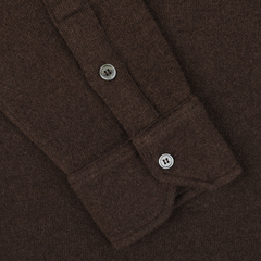 Close-up of the cuff of the luxurious Dark Brown Felted Cashmere Overshirt by Fedeli, highlighting its elegant brown long-sleeved design with one button fastened and another on the placket.