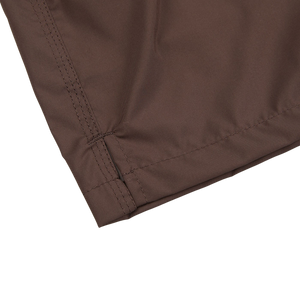 A close up of Fedeli Dark Brown Microfiber Madeira Swim Shorts, a luxury casual wear, on a white surface.
