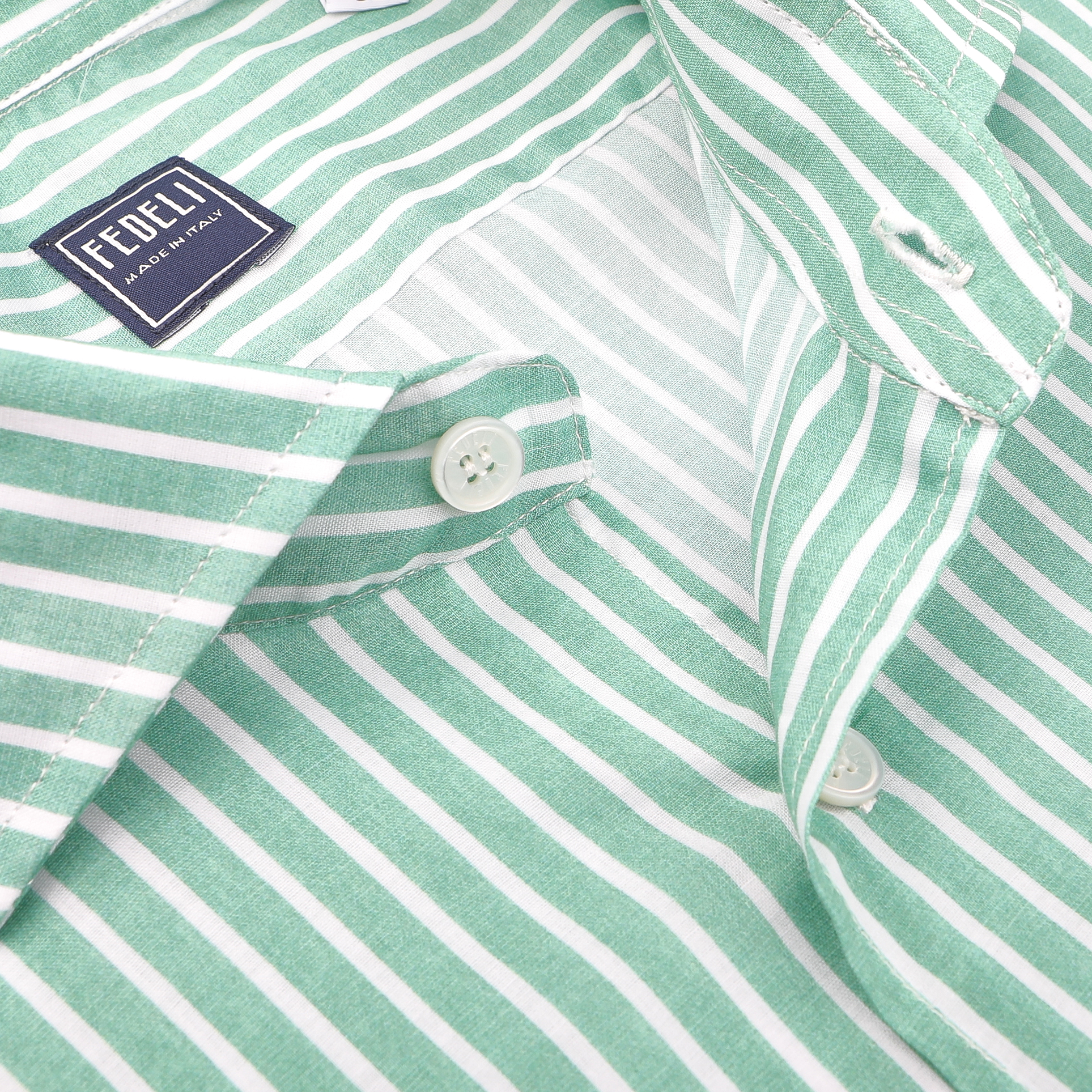 Close-up of a Fedeli "Made in Italy" label on a slim-fit Green White Striped Cotton Beach Shirt featuring white buttons, crafted from stretch cotton fabric, and neatly folded.