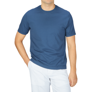 A man wearing a Fedeli Indigo Blue Organic Cotton T-Shirt and white pants.