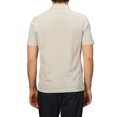 A person wearing a Fedeli Light Beige Organic Cotton Capri Collar Polo Shirt is paired with black pants, standing against a gray background.