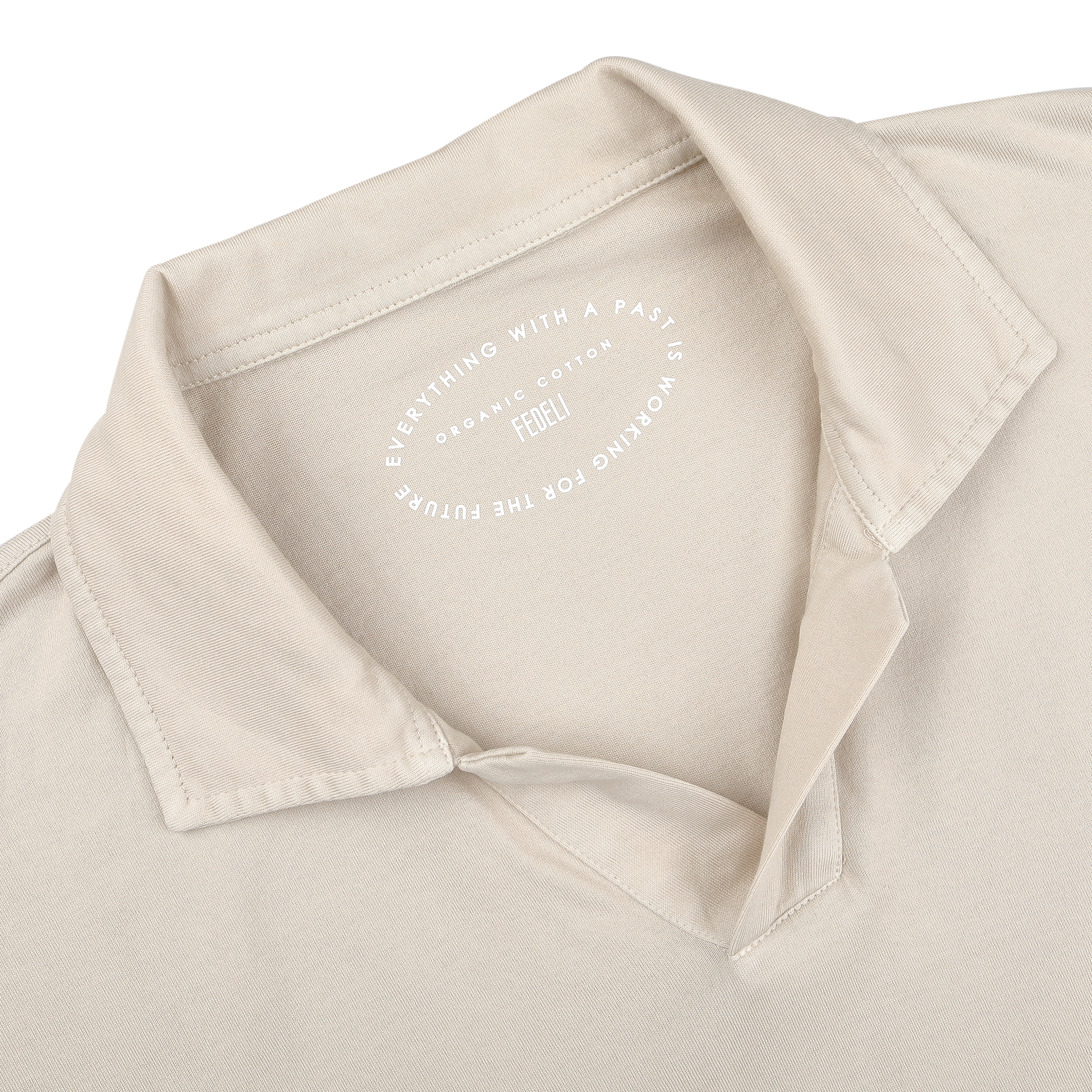 Close-up of the Light Beige Organic Cotton Capri Collar Polo Shirt by Fedeli shows an open capri collar and a visible inner label reading, "Everything with a past is working for future." Crafted from organic Giza cotton, it blends luxury casual-wear with sustainability.