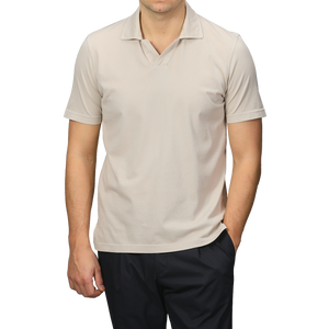 A person wears the Light Beige Organic Cotton Capri Collar Polo Shirt by Fedeli, with dark pants, one hand in the pocket, and faces forward.