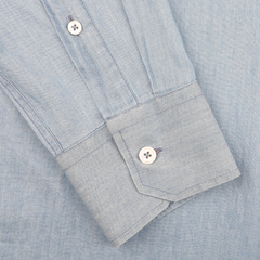 A light blue cotton denim shirt by Fedeli, featuring a slim fit design with casual shirt cuffs and two white buttons, is buttoned and lying flat.