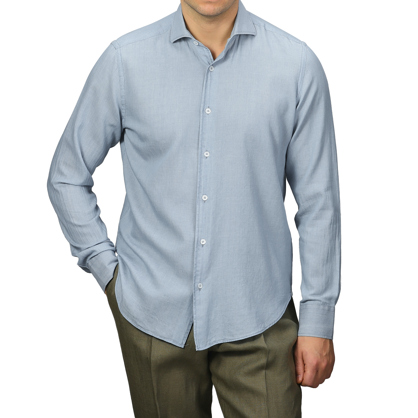 A person dressed in a Fedeli Light Blue Cotton Denim Shirt and olive green pants stands with one hand in their pocket against a plain gray background.