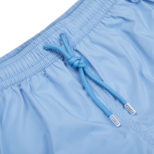 A luxurious pair of Fedeli Light Blue Microfiber Madeira swim shorts with a blue drawstring.