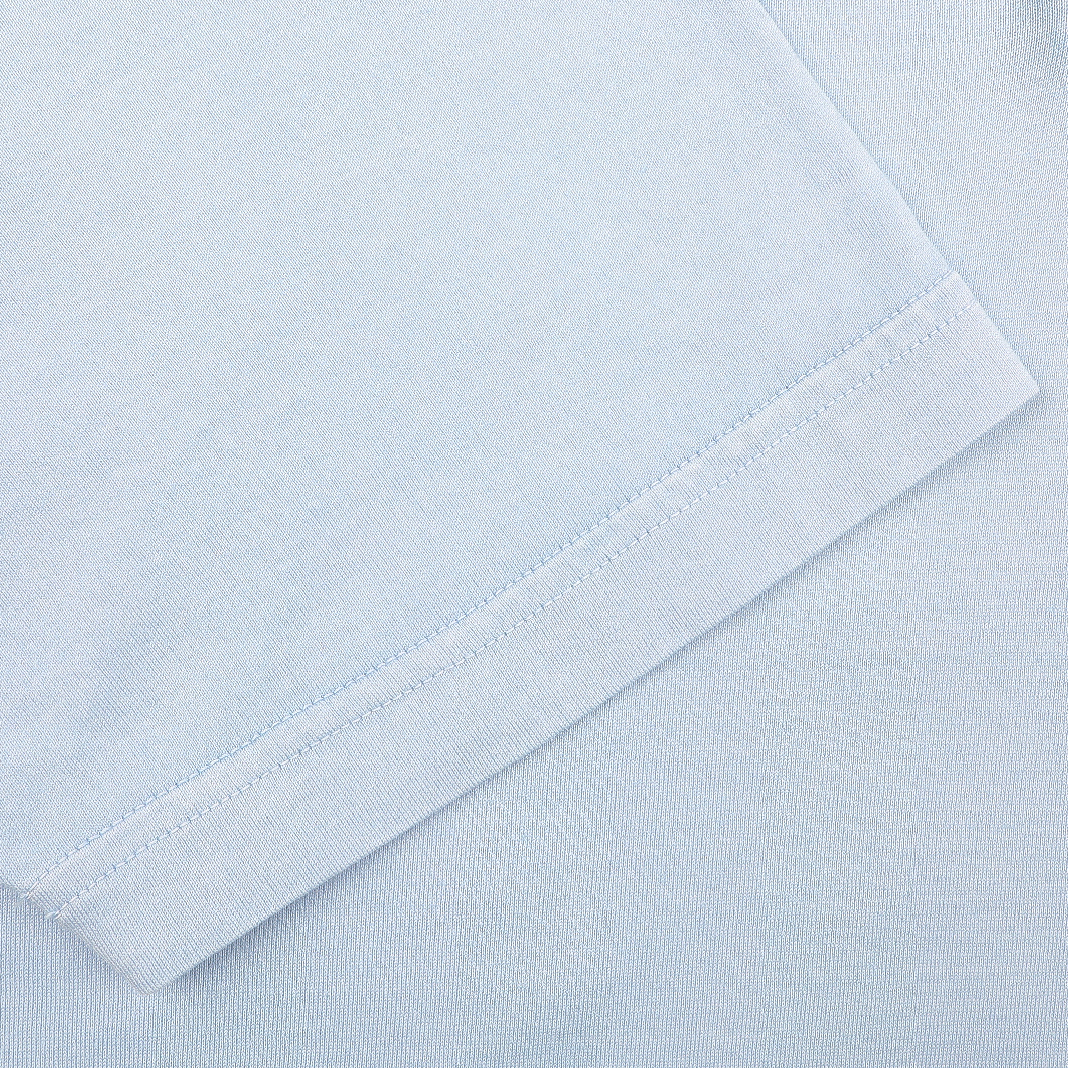 Close-up of a Fedeli Light Blue Organic Cotton Capri Collar Polo Shirt, highlighting the fine stitched hem made from organic Giza cotton.