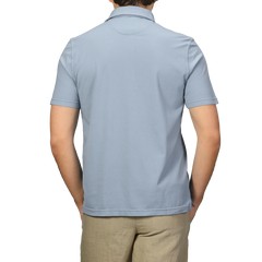 Rear view of a person in a Fedeli Light Blue Organic Cotton Polo Shirt and beige pants, standing against a plain background.