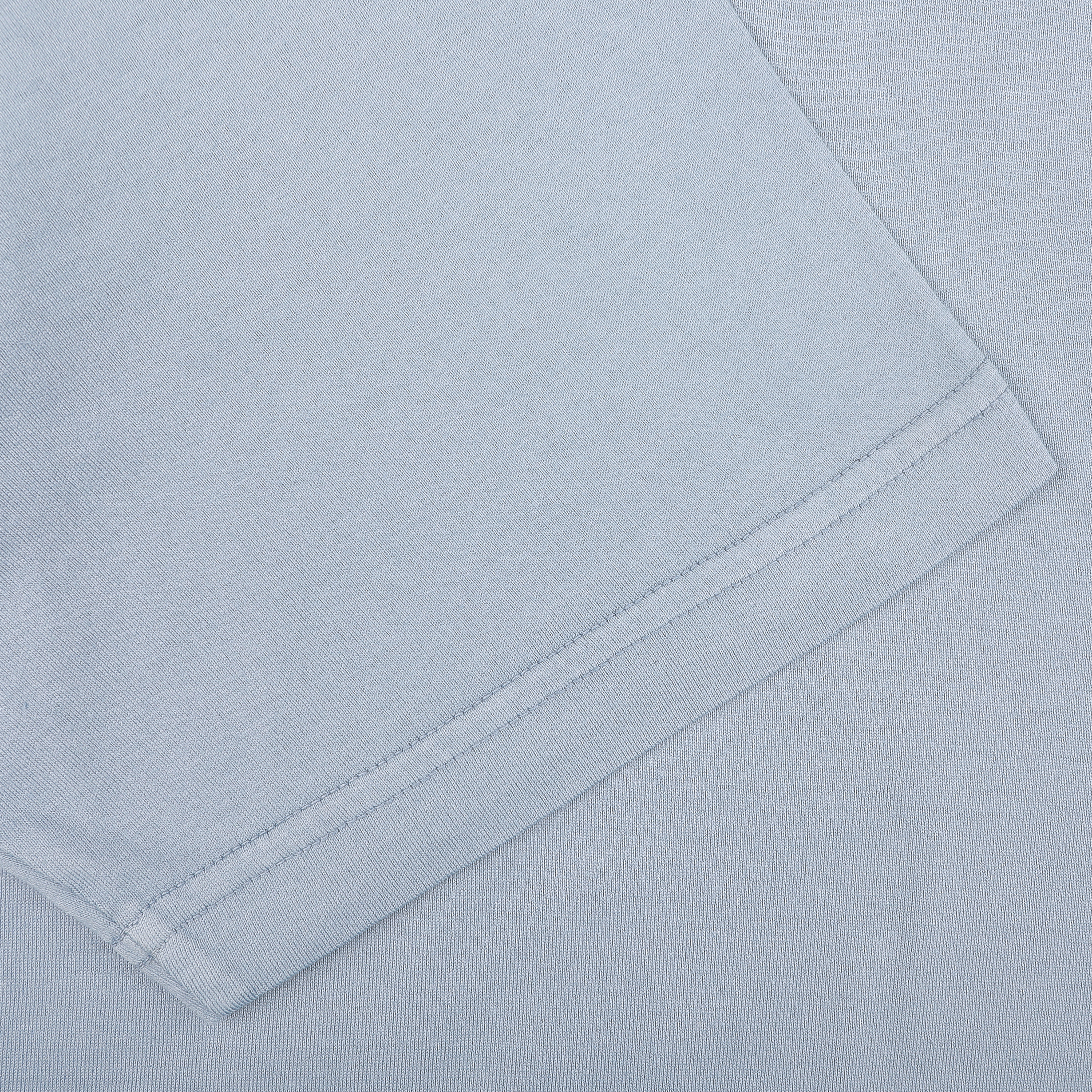 A close-up shows the sleeve of a Fedeli Light Blue Organic Cotton Polo Shirt, featuring visible stitching along the hem.