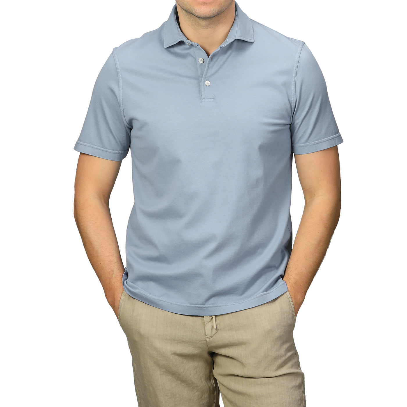 A person in a light blue organic cotton polo shirt by Fedeli and beige pants, showcasing luxury casual-wear, stands with hands in pockets against a gray background.