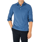 A man wearing a Light Blue Organic Cotton LS Polo Shirt by Fedeli and black pants.