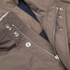 A close-up of Fedeli's Light Brown Nylon Rainproof Field Jacket showcases its silver zipper and button closures against a dark fabric backdrop. The wind and water-resistant design ensures both style and practicality.