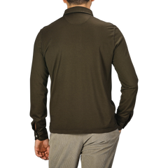 A man wearing a Fedeli Moss Green Organic Cotton LS Polo Shirt and beige pants is shown from behind against a plain background.