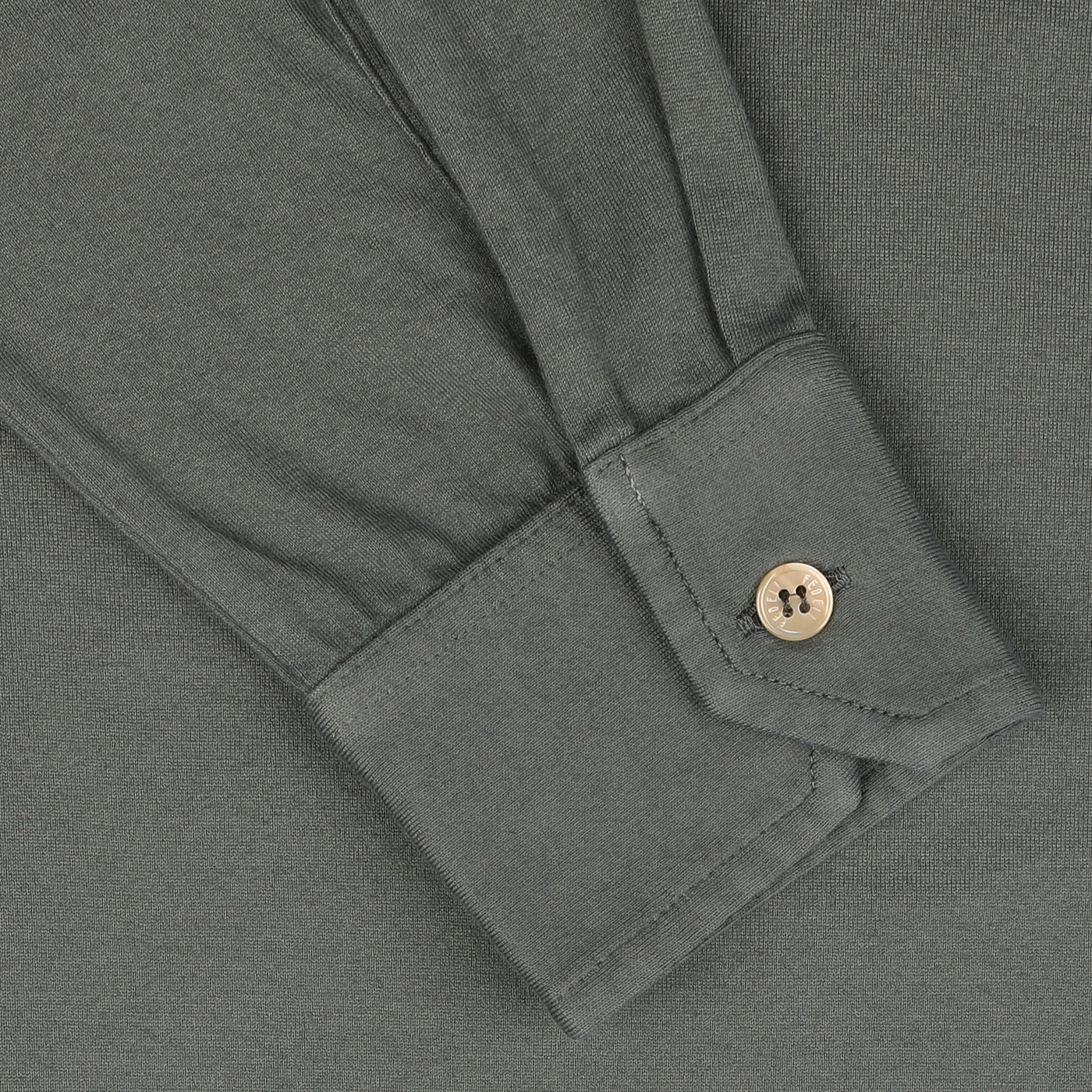 Close-up of the sleeve of a Muted Green Organic Cotton LS Polo Shirt from Fedeli, featuring a buttoned cuff. The fabric appears smooth, with visible stitching detail around the cuff and buttonhole, exemplifying luxury casual-wear.