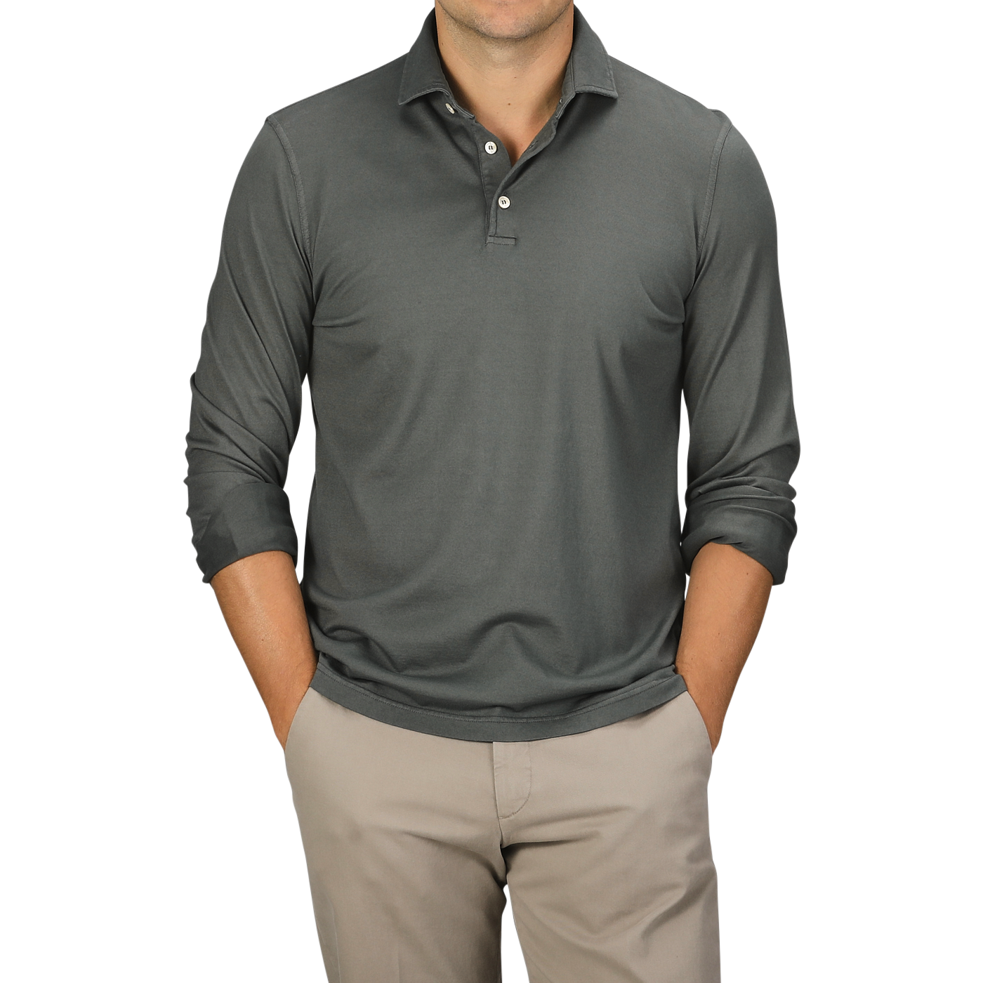 A man wearing a Muted Green Organic Cotton LS Polo Shirt by Fedeli and beige pants stands with his hands in his pockets against a plain background, embodying luxury casual-wear.