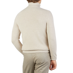 A person wears the Fedeli Natural Beige Wool Cashmere Rollneck sweater with matching pants, seen from the back against a plain background.