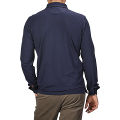 An individual is wearing a Fedeli Navy Blue Organic Cotton LS Polo Shirt and brown trousers, viewed from the back against a plain background.