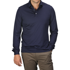 A man is wearing a Navy Blue Organic Cotton LS Polo Shirt by Fedeli and beige pants, with hands partially in pockets, epitomizing luxury casual wear.